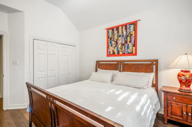 a bedroom with a bed a dresser and a large window