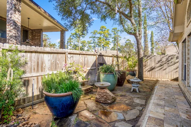 a view of a yard with plants and a brick wall