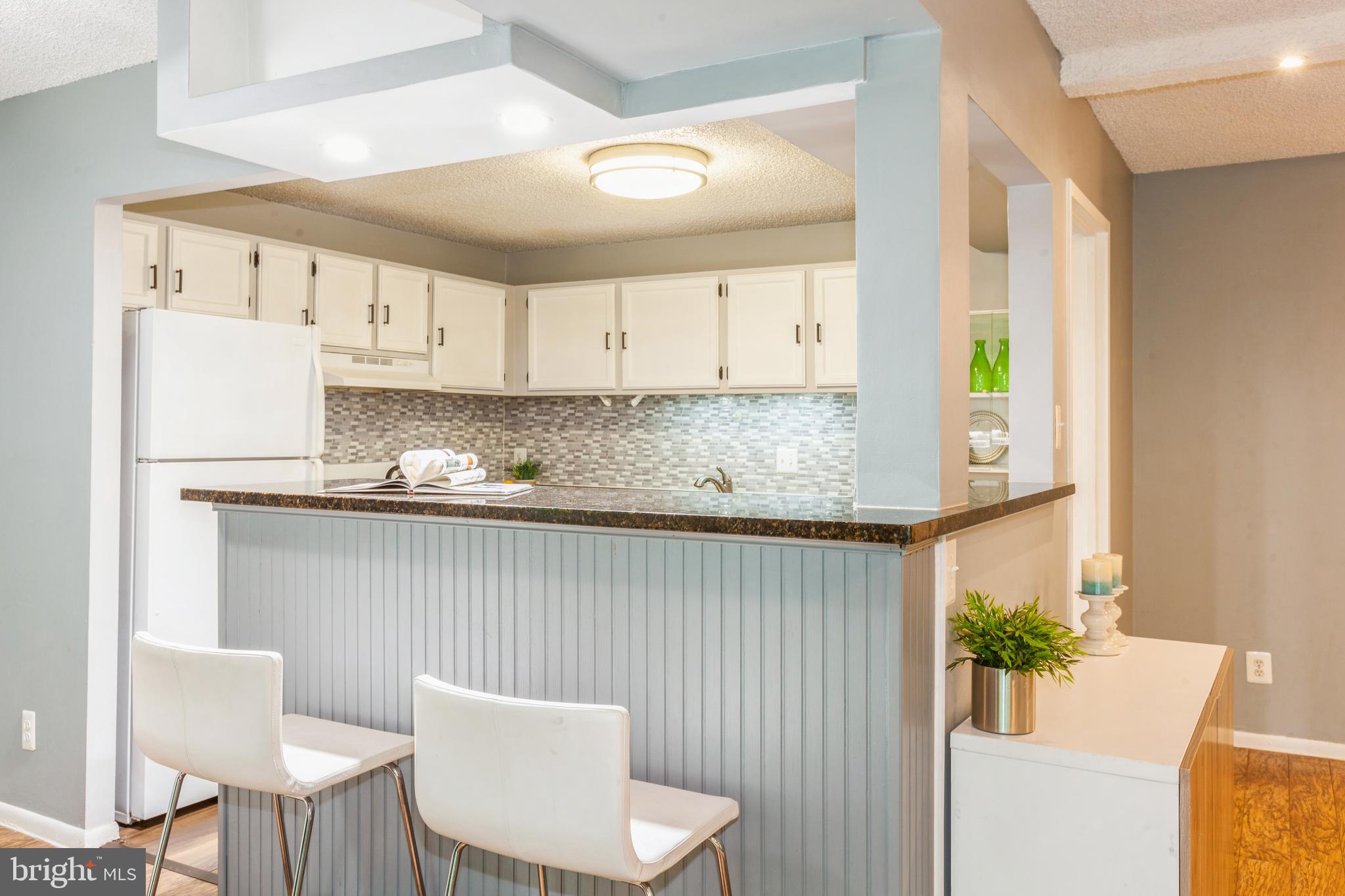 11833 Shire Court, Unit 12C Reston, VA 20191 - Photo 8 of 28 a kitchen with a white table chairs and a refrigerator