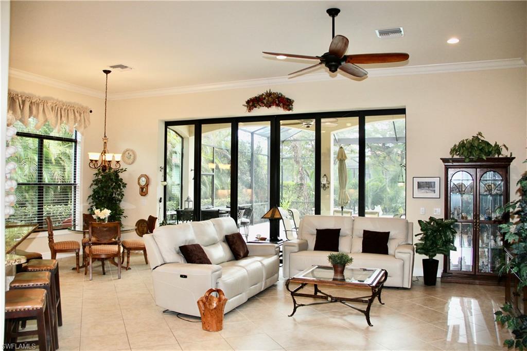 9321 Vercelli Court Naples, FL 34113 - Photo 13 of 49 a living room with furniture ceiling fan floor to ceiling windows and a ceiling fan