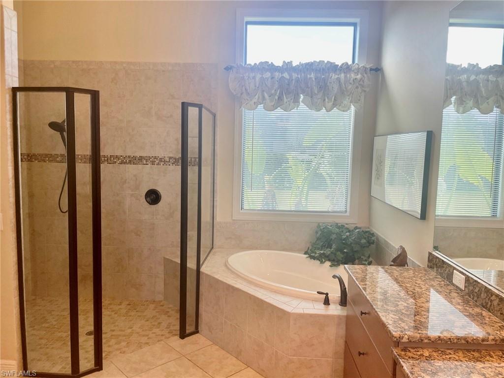 9321 Vercelli Court Naples, FL 34113 - Photo 42 of 49 a bathroom with a granite countertop tub sink and glass door