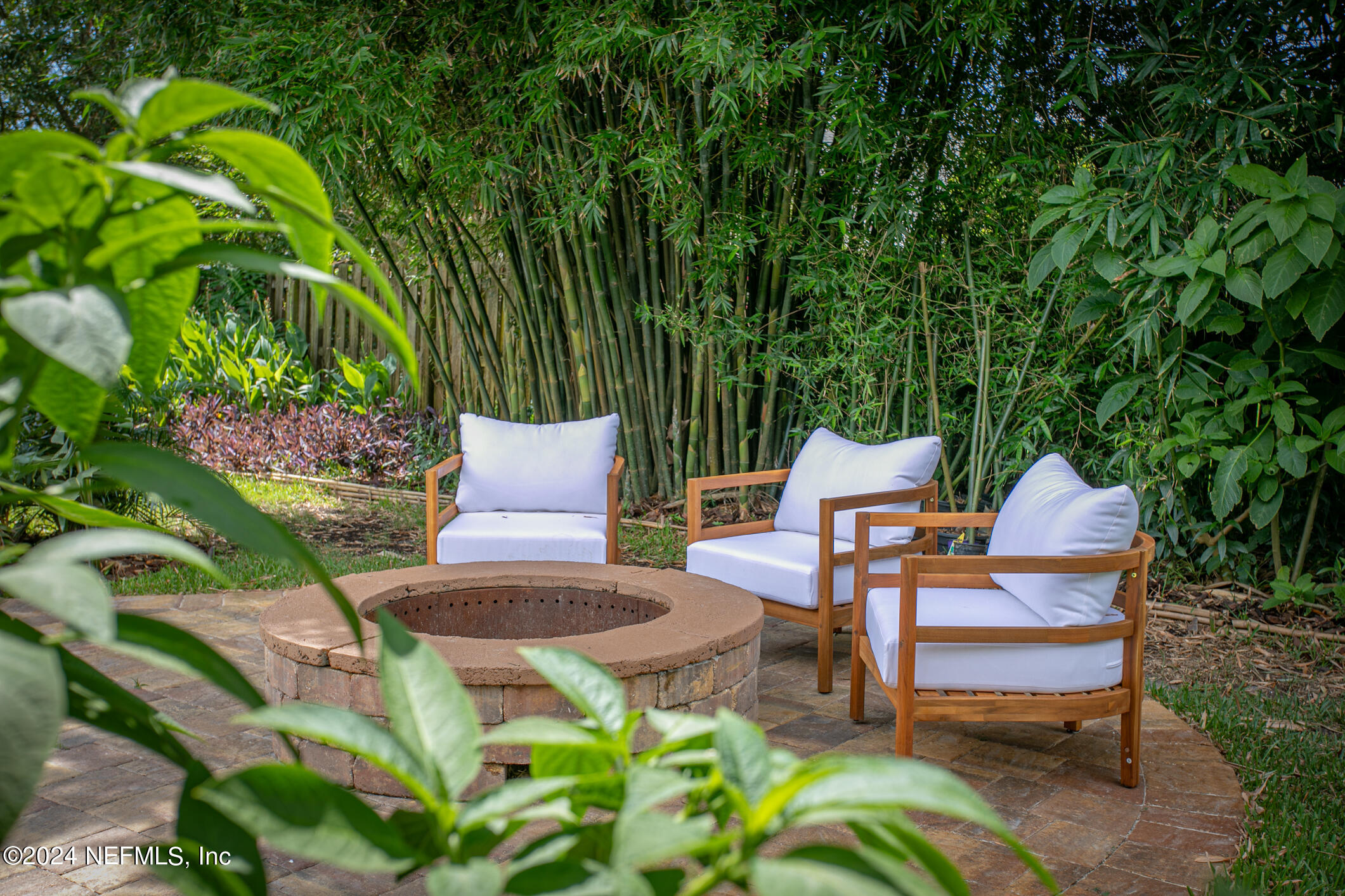 622 Cherry Street Neptune Beach, FL 32266 - Photo 53 of 77 a wooden bench sitting in backside of a house with potted plants and large trees