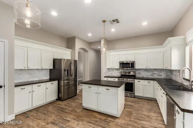 a kitchen with stainless steel appliances granite countertop a sink stove refrigerator and cabinets