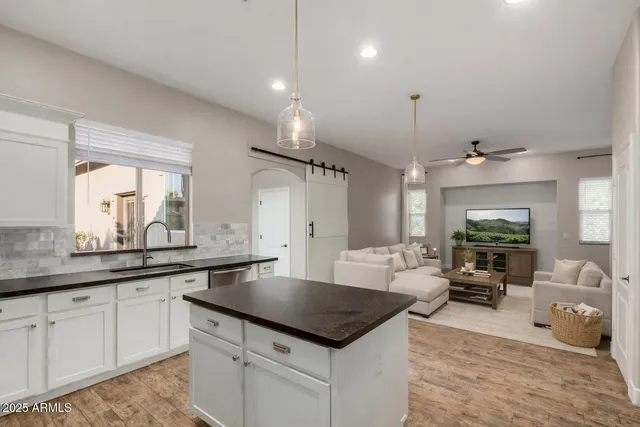 a kitchen with a stove a sink and white cabinets with wooden floor