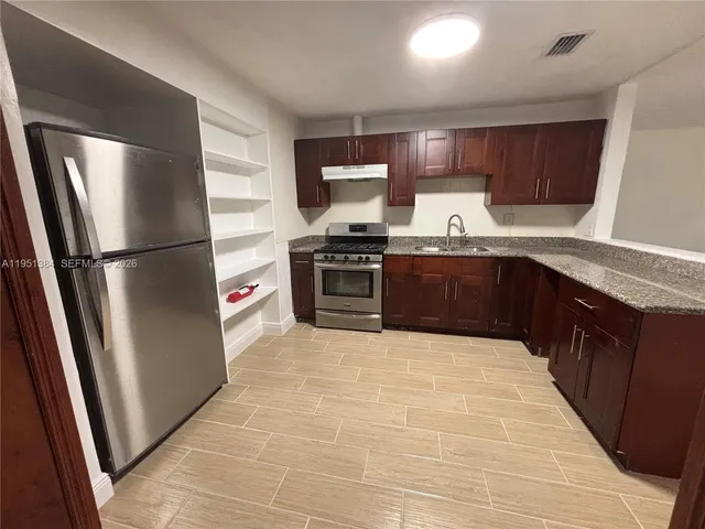 a large kitchen with stainless steel appliances granite countertop a stove a sink dishwasher and a refrigerator