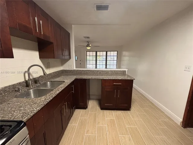 a kitchen with granite countertop a sink a stove cabinets and wooden floor