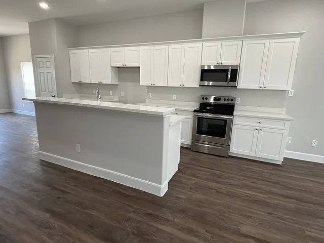 a kitchen with stainless steel appliances granite countertop a stove a sink and white cabinets