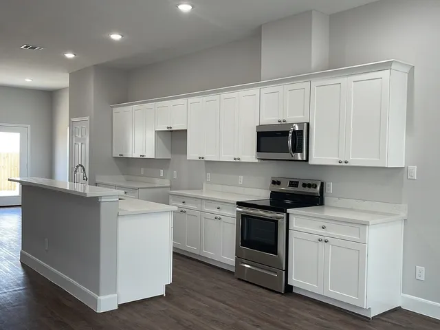 a kitchen with white cabinets and black appliances