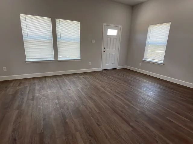 an empty room with wooden floor and windows