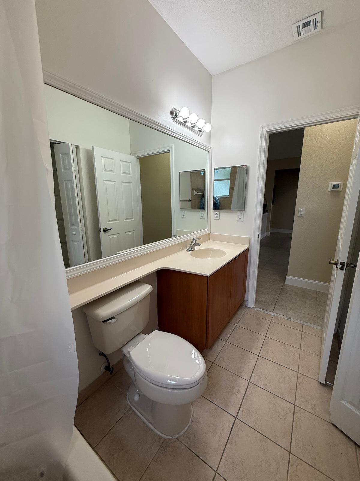 3569 Forest Hill Boulevard, Unit 110 Palm Springs, FL 33406 - Photo 19 of 23 a bathroom with a sink a toilet a mirror and bathtub