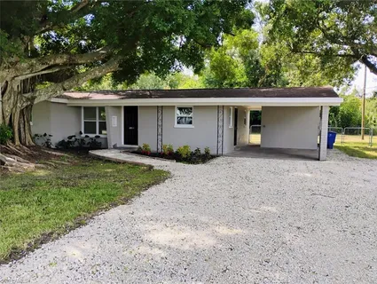 a view of a house with a yard and large trees