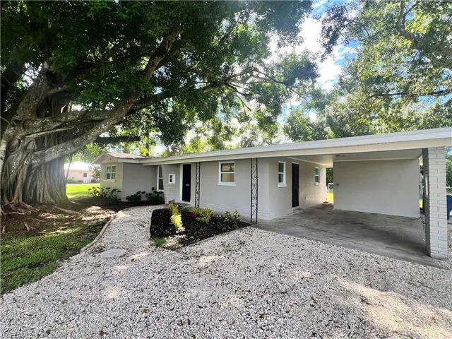 a front view of house with yard and trees in the background