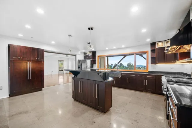a kitchen with stainless steel appliances kitchen island granite countertop a refrigerator and a stove top oven