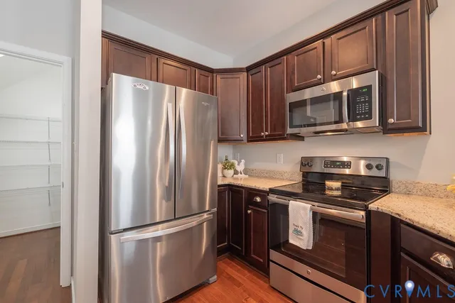 a kitchen with granite countertop a refrigerator stove and microwave
