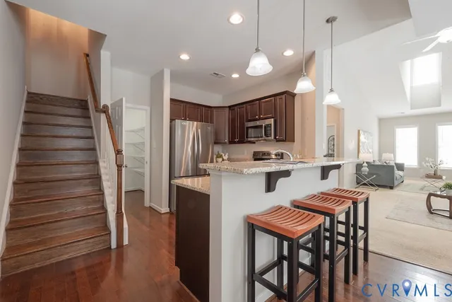 a kitchen with stainless steel appliances kitchen island granite countertop a refrigerator and a stove top oven