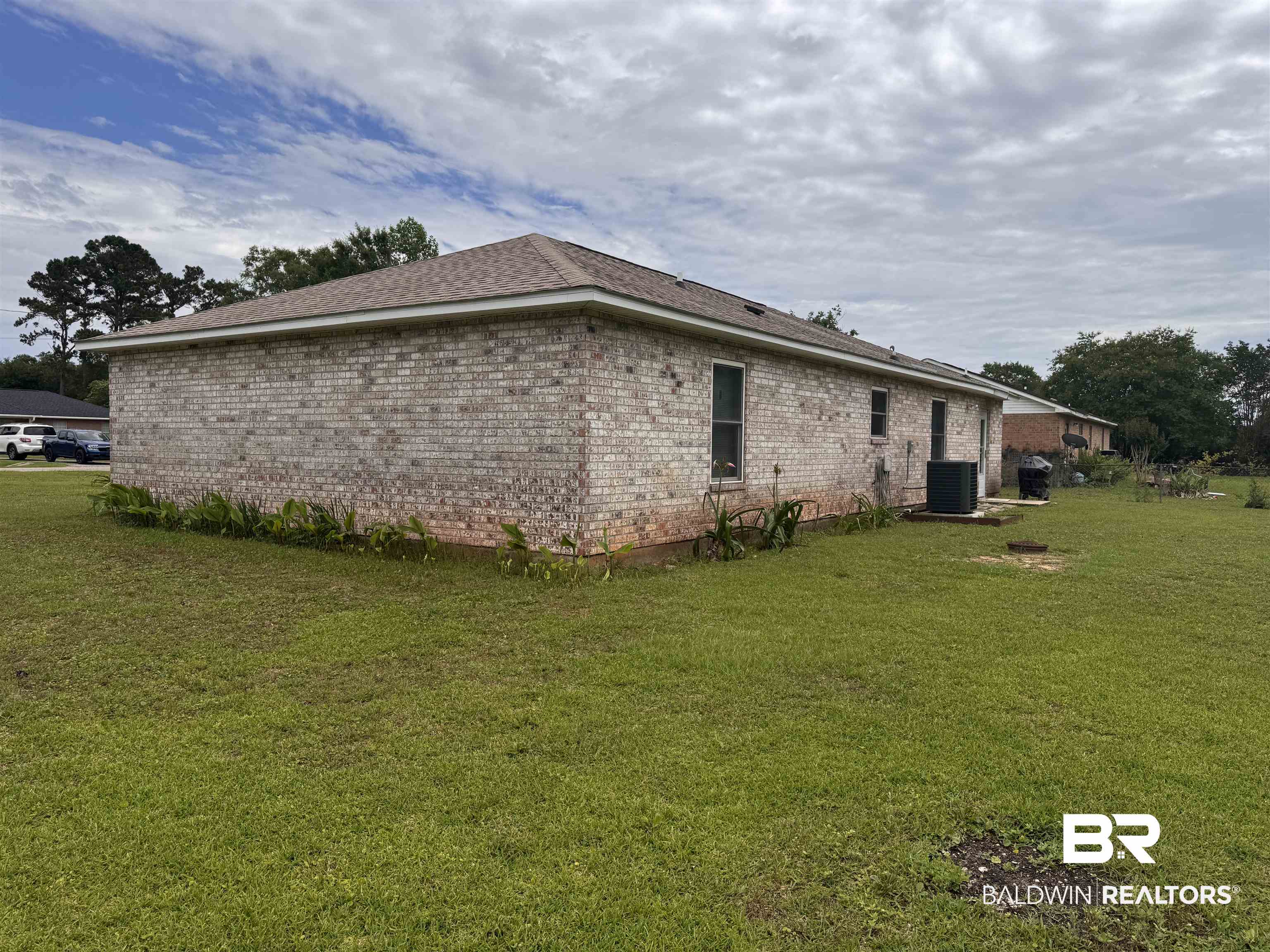 15148 Highland Circle Foley, AL 36535 - Photo 4 of 47 View of property exterior featuring central AC unit, a lawn, and brick siding