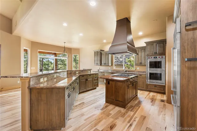 a kitchen with stainless steel appliances kitchen island granite countertop a refrigerator and a stove top oven
