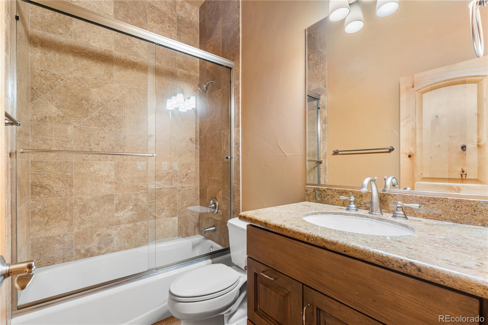 691 Cumberland Road Larkspur, CO 80118 - Photo 26 of 43 a bathroom with a granite countertop sink toilet and shower