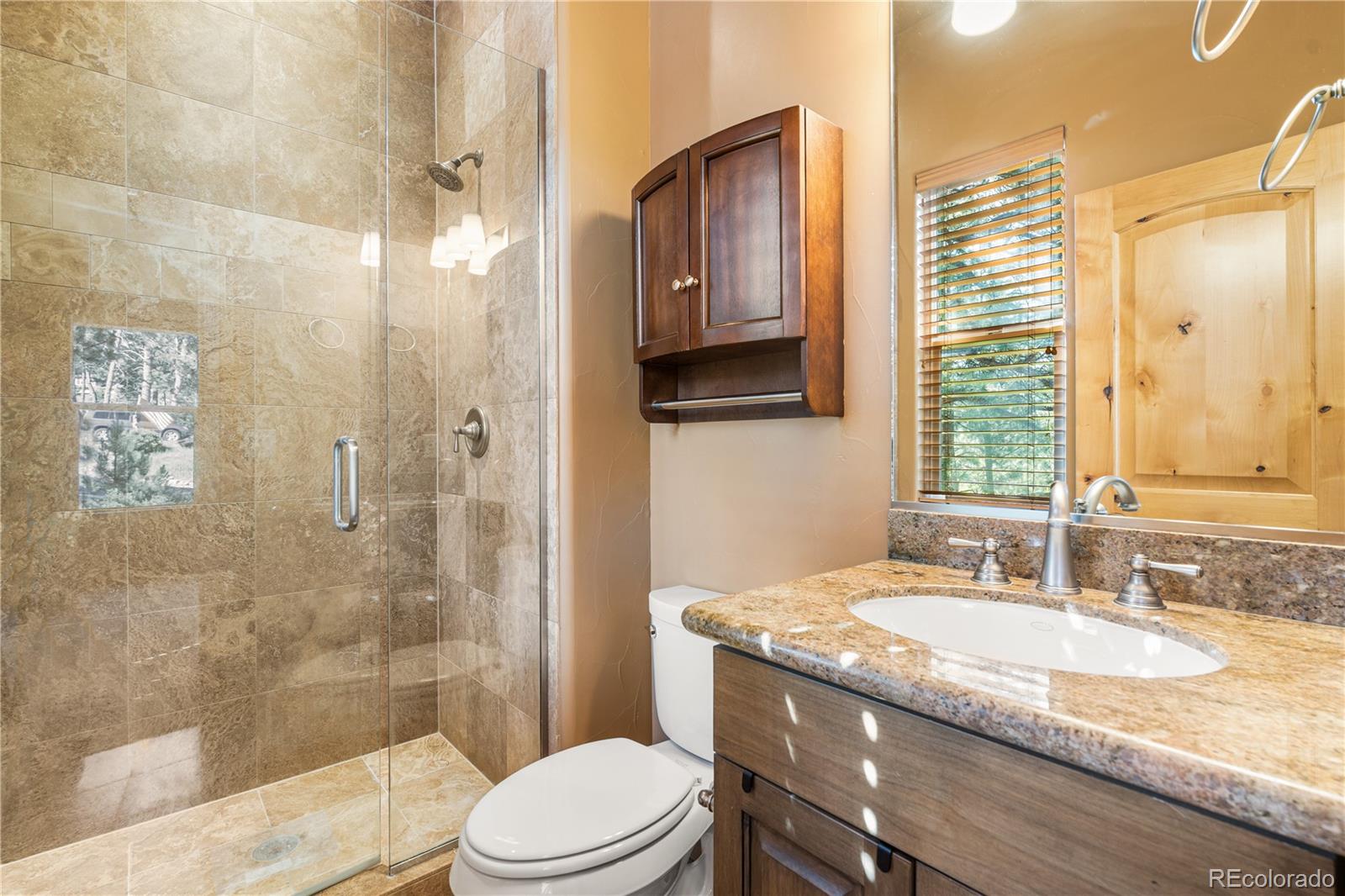 691 Cumberland Road Larkspur, CO 80118 - Photo 28 of 43 a bathroom with a granite countertop sink a toilet a mirror and shower