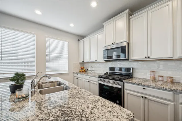 a kitchen with granite countertop a sink a stove and cabinets