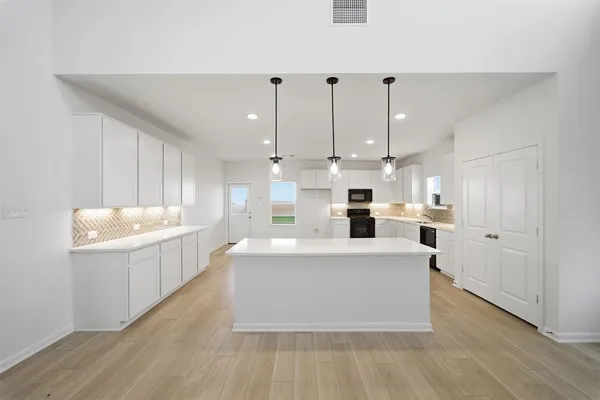 a large white kitchen with kitchen island a sink a center island and a stove