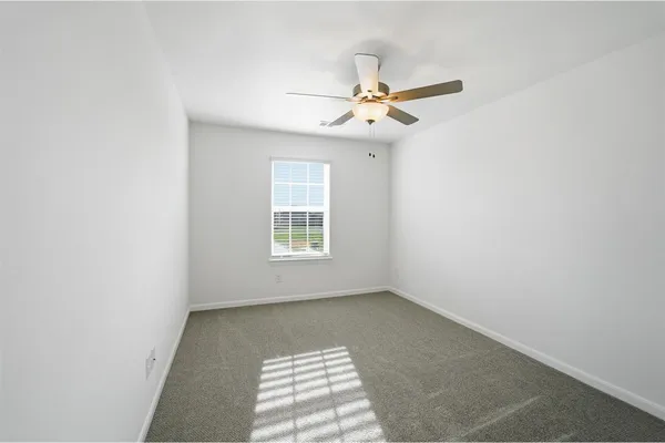 an empty room with a window and a fan
