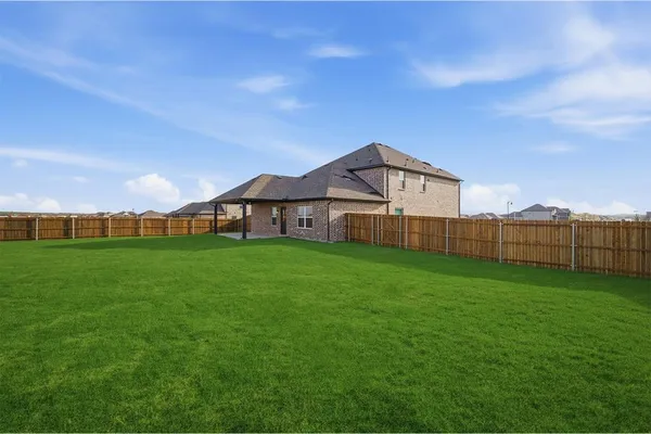 a view of a wooden house with a big yard and large trees