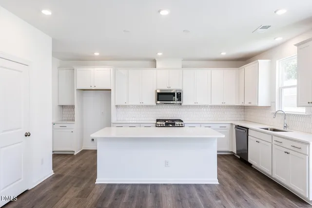 a kitchen with stainless steel appliances white cabinets and wooden floor