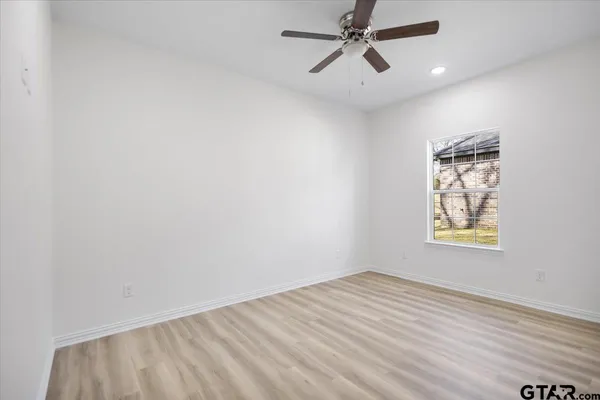 an empty room with windows and fan