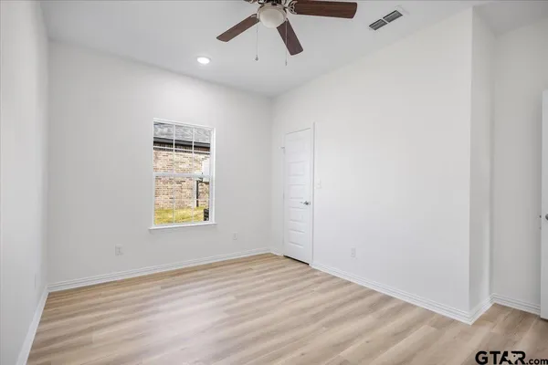 an empty room with a window and ceiling fan