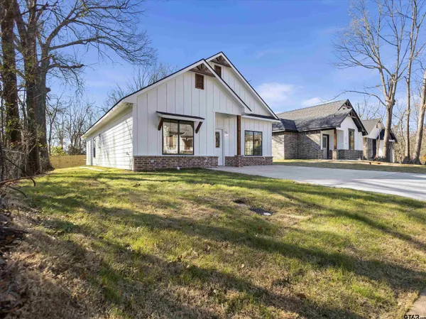 a front view of house with yard and trees in the background