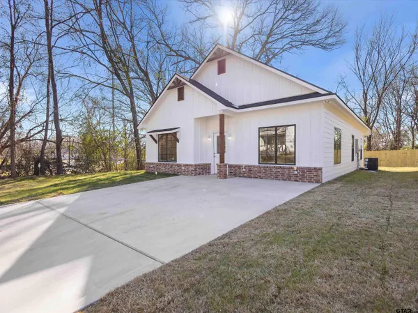 a view of a white house with a yard and large tree
