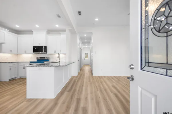 a large kitchen with stainless steel appliances granite countertop a stove a sink dishwasher and a refrigerator with wooden floor