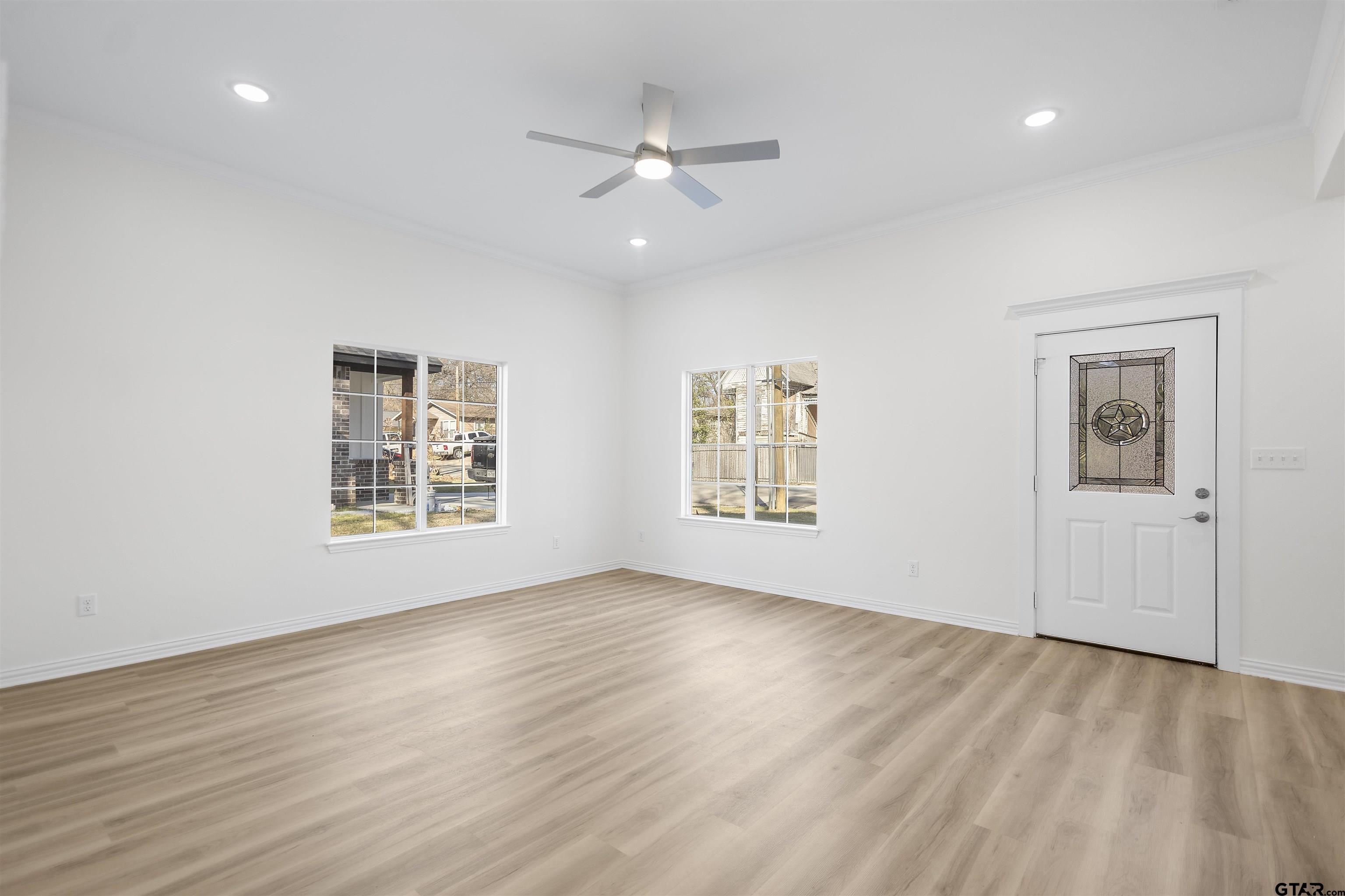 1310 West Claude Street Tyler, TX 75702 - Photo 6 of 27 an empty room with wooden floor ceiling fan and windows