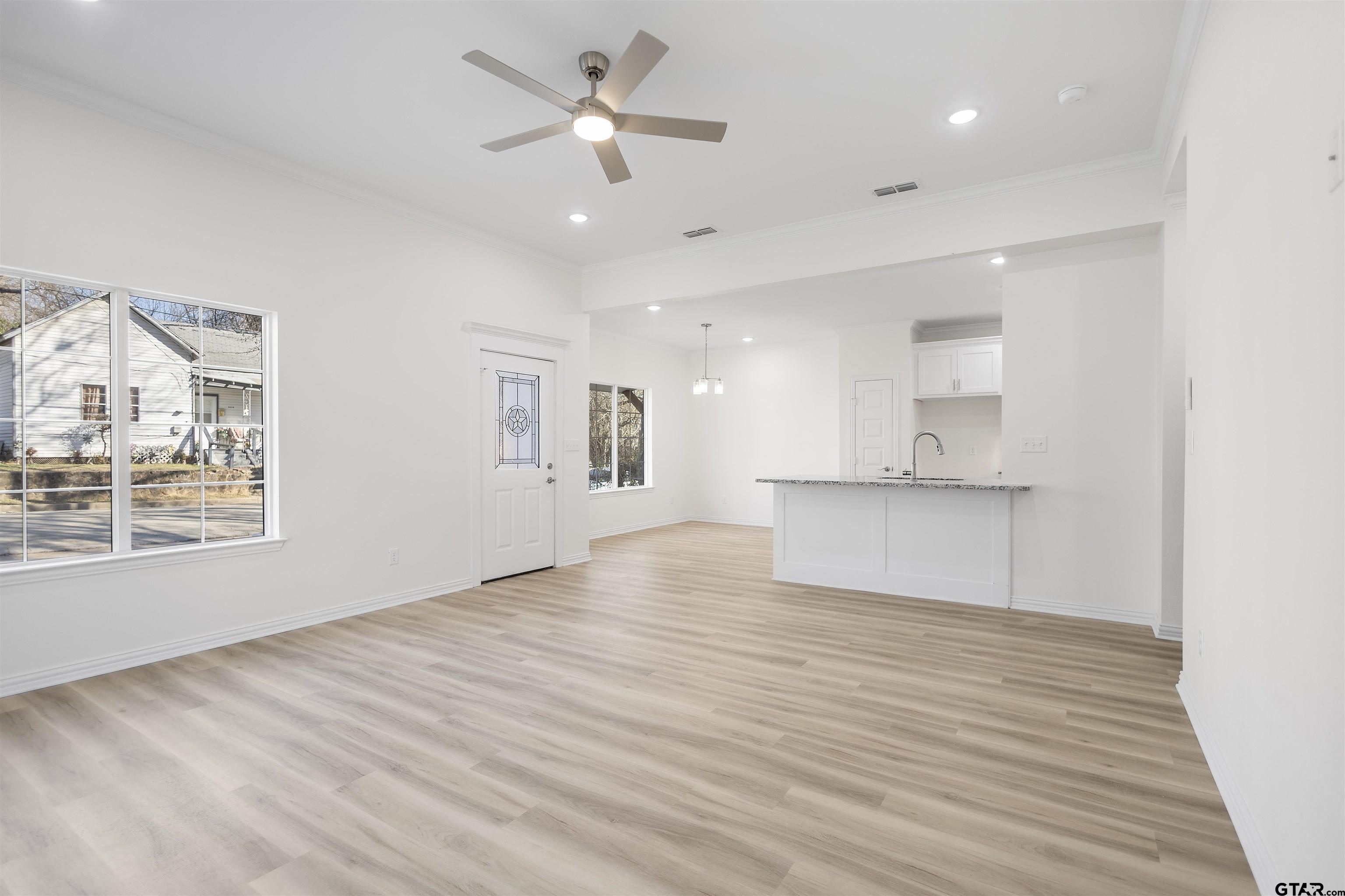 1310 West Claude Street Tyler, TX 75702 - Photo 9 of 27 a view of an empty room with a window and wooden floor