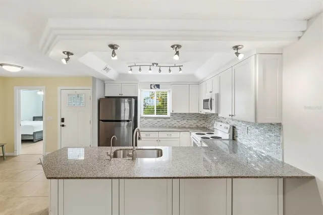 a kitchen with kitchen island granite countertop a sink and refrigerator