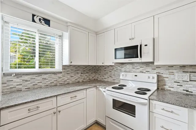 a kitchen with granite countertop white cabinets and white appliances