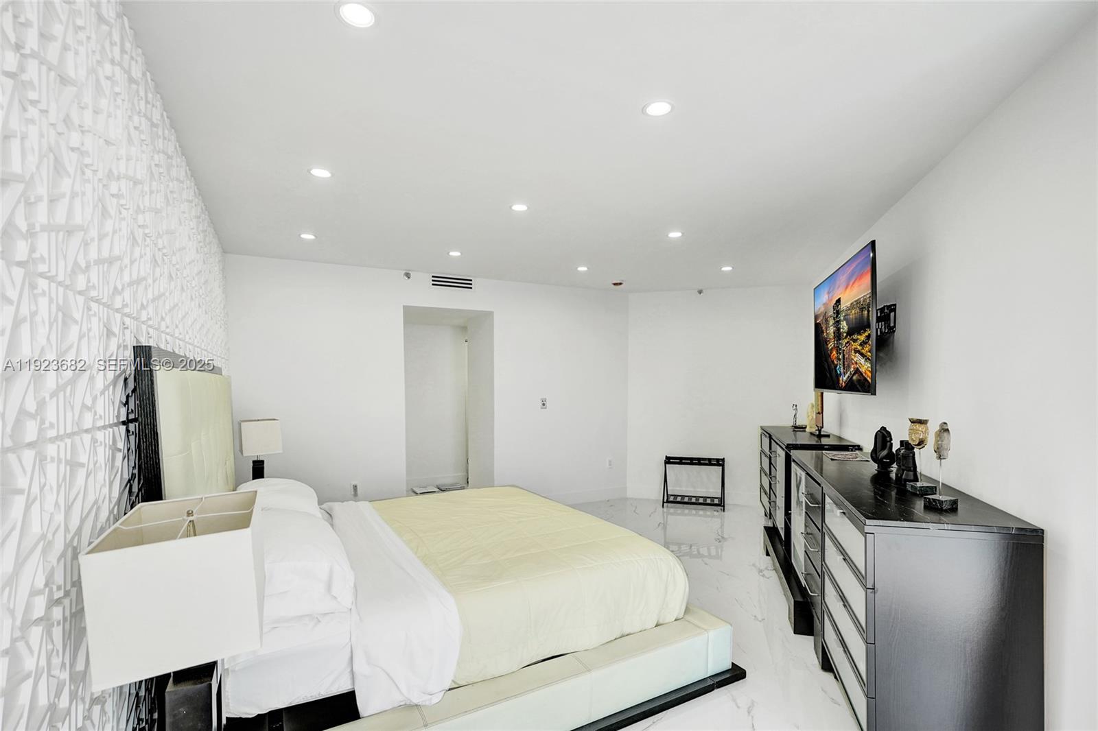 4000 Island Boulevard, Unit 2301 Aventura, FL 33160 - Photo 33 of 50 a bedroom with a bed and flat screen tv