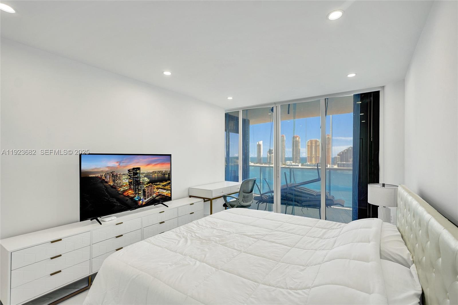 4000 Island Boulevard, Unit 2301 Aventura, FL 33160 - Photo 37 of 50 a bedroom with a bed and a flat screen tv