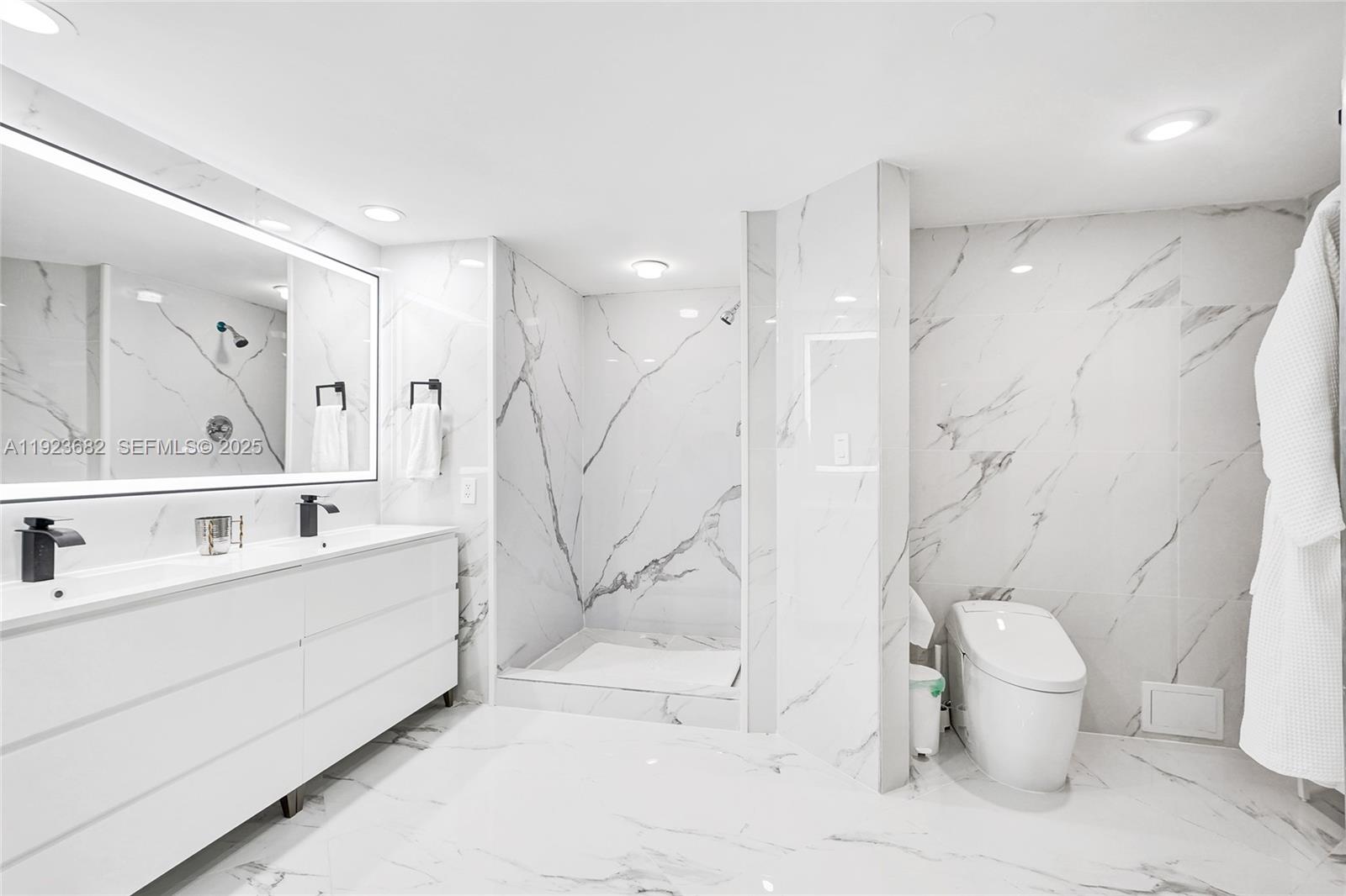 4000 Island Boulevard, Unit 2301 Aventura, FL 33160 - Photo 4 of 50 a bathroom with a sink a toilet and a large mirror