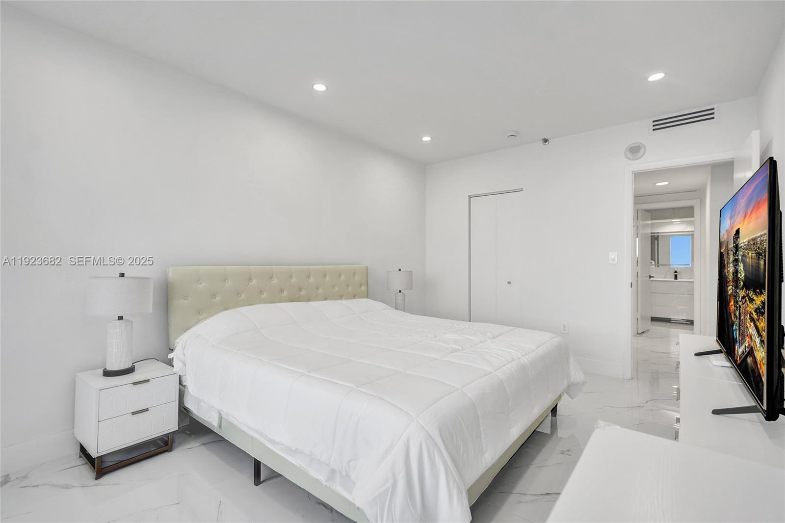 4000 Island Boulevard, Unit 2301 Aventura, FL 33160 - Photo 41 of 50 a bedroom with a bed and a flat screen tv