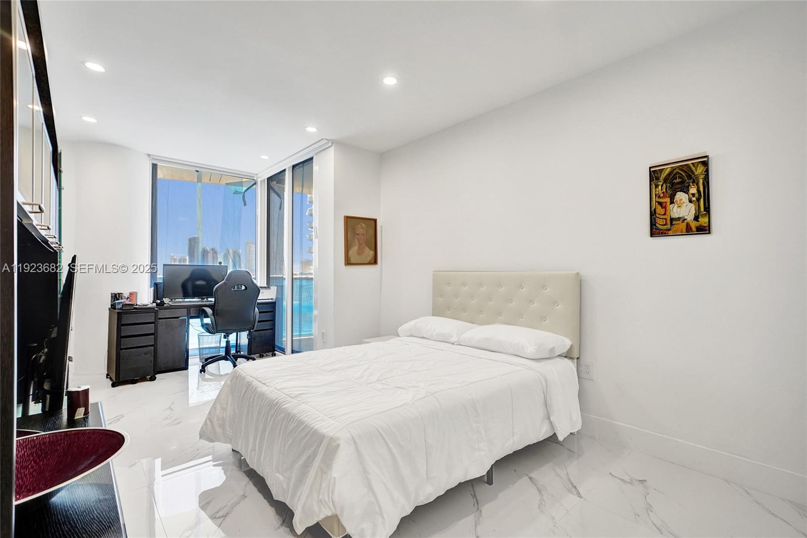 4000 Island Boulevard, Unit 2301 Aventura, FL 33160 - Photo 45 of 50 a bedroom with a bed a couch and a flat tv screen on the dresser