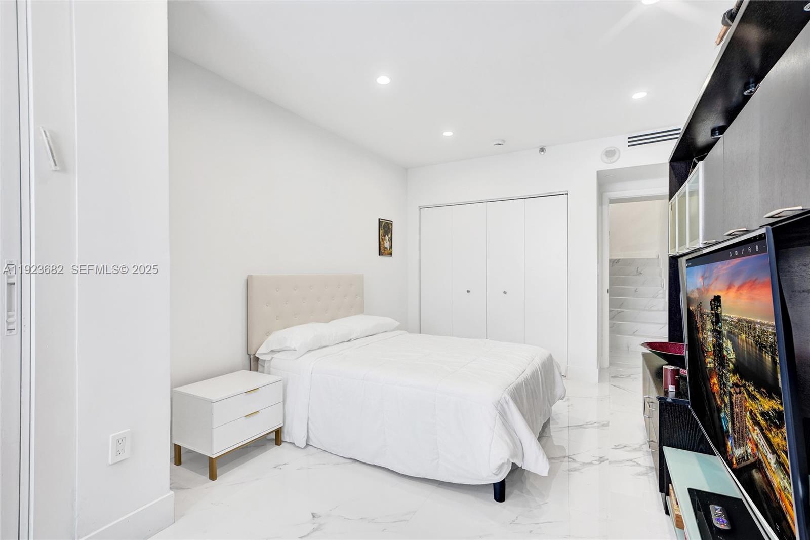 4000 Island Boulevard, Unit 2301 Aventura, FL 33160 - Photo 47 of 50 a bedroom with a bed and a flat screen tv