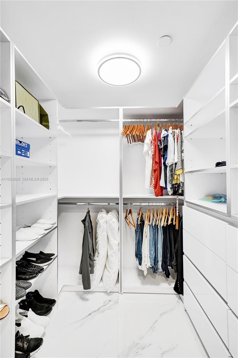 4000 Island Boulevard, Unit 2301 Aventura, FL 33160 - Photo 49 of 50 a view of walk in closet with clothes and shoes