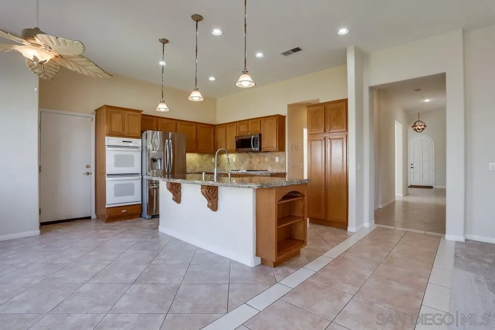 710 Greyfield Court Fallbrook, CA 92028 - Photo 12 of 28 a large kitchen with stainless steel appliances kitchen island granite countertop a refrigerator and a sink