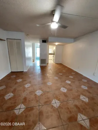 an empty room with wooden floor fan and windows