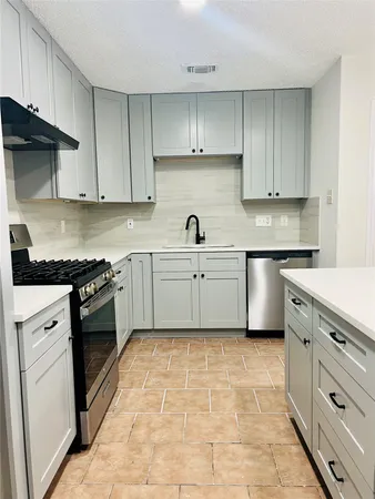 a kitchen with cabinets stainless steel appliances and sink