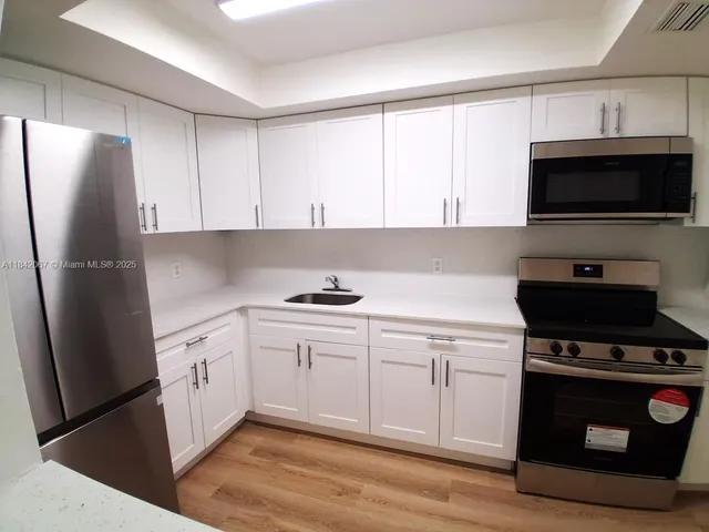 a kitchen with stainless steel appliances a stove a sink and a refrigerator