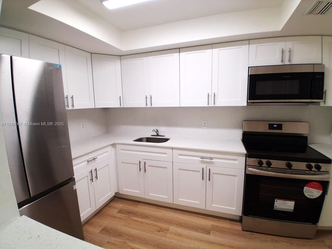 a kitchen with stainless steel appliances a stove a sink and a refrigerator