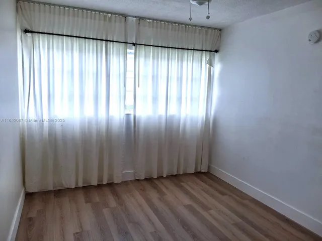 an empty room with wooden floor closet and fan